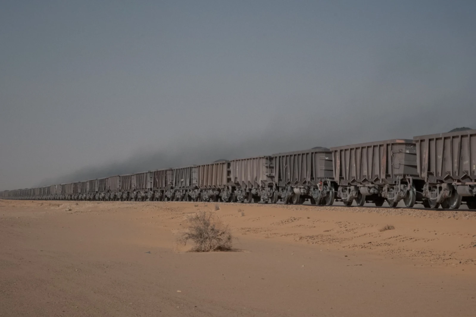A long line of iron-ore wagons crossing open desert in northern Mauritania.