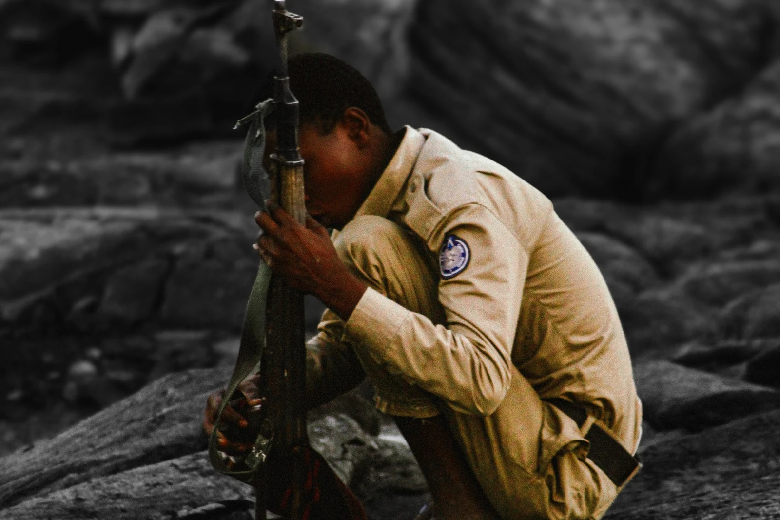 A member of the local militia seated on volcanic ground near the summit.