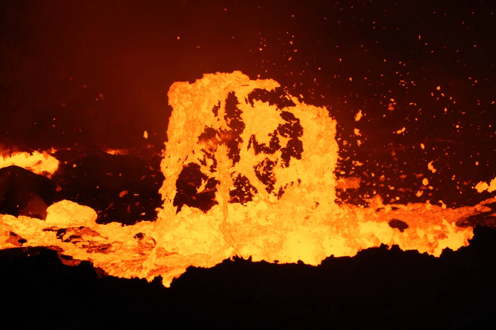 Molten lava rising above the dark crust and collapsing back into the crater.