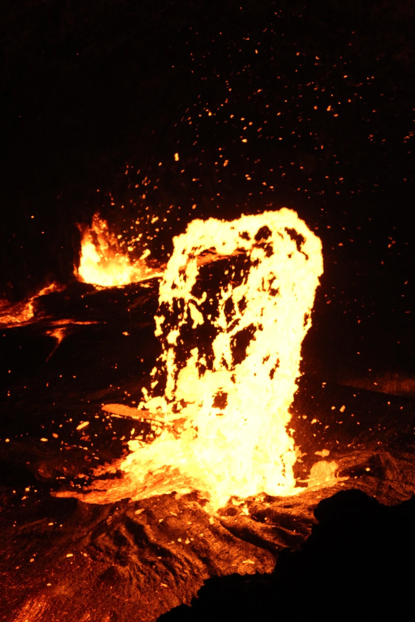 A vertical surge of molten lava against the dark summit.