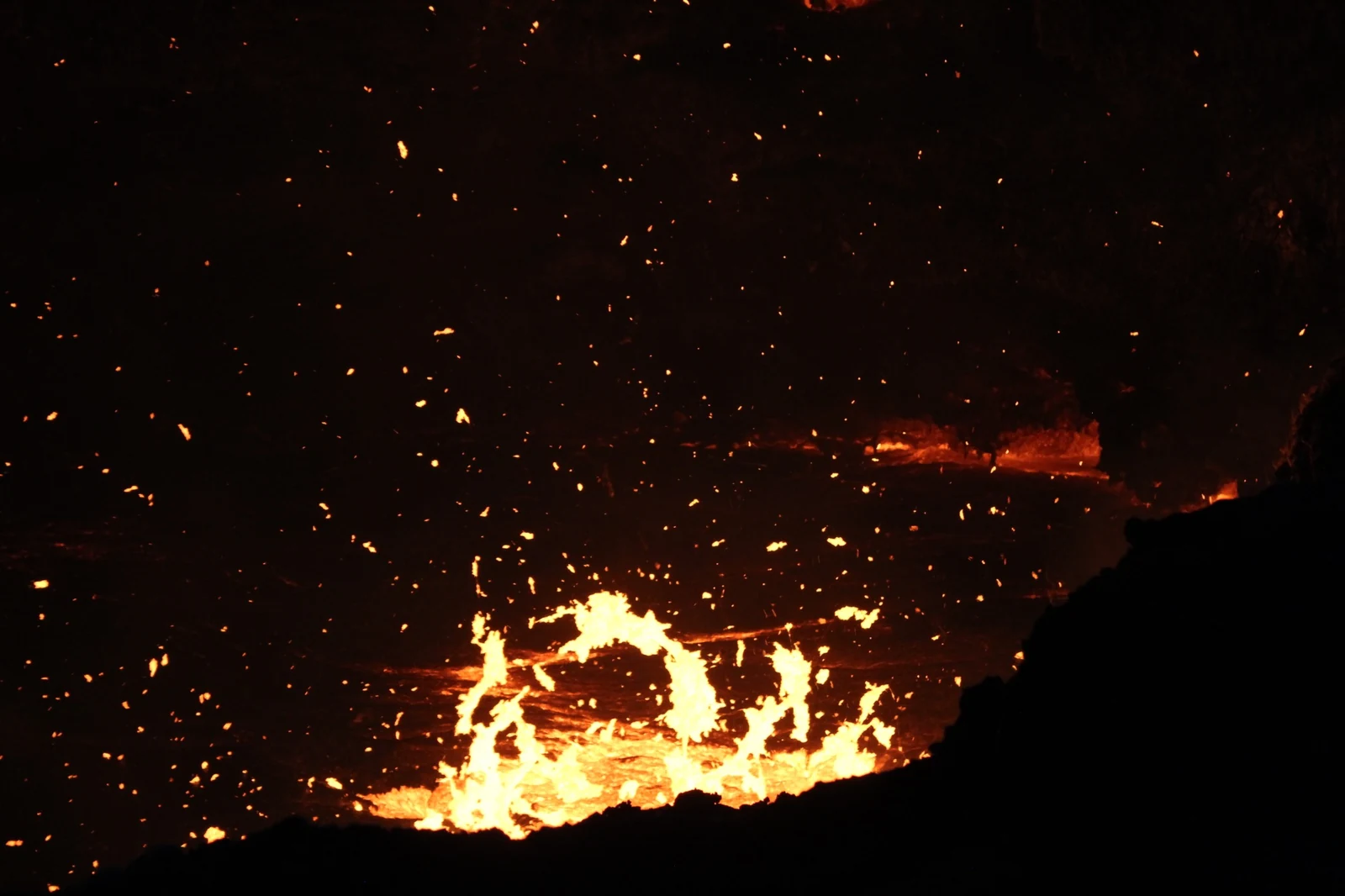 Incandescent fragments above the active surface as the dark crust breaks.